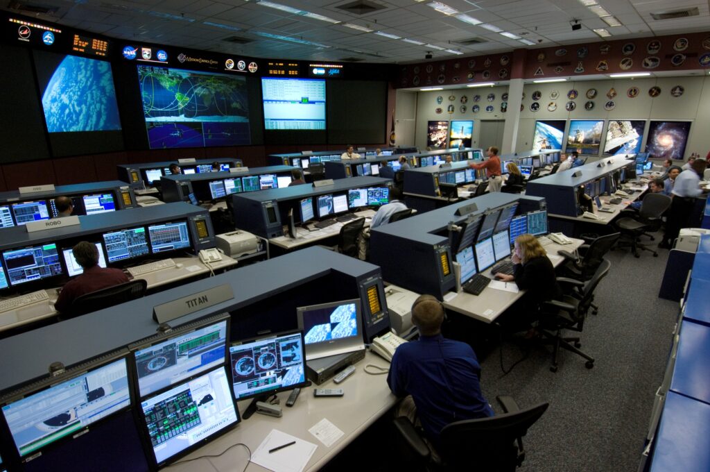 NASA flight controllers at their consoles in the ISS Flight Control Room at Johnson Space Center. NASA photo by Robert Markowitz (public domain).